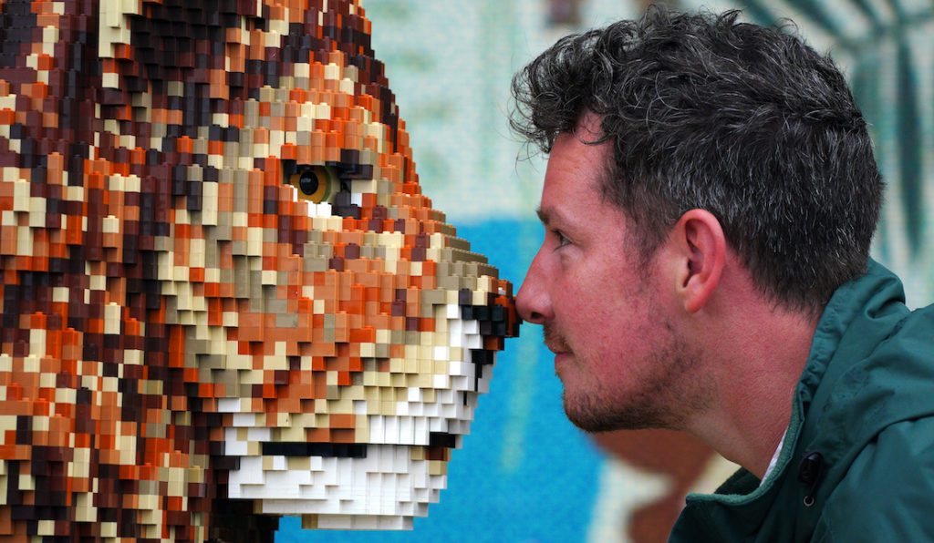 A member of staff at Knowsley Safari park is nose to nose with a brick lion, part of the summer display
